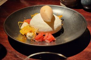 Pavlova topped with grapefruit sorbet and garnished with dollops of honey yogurt and supreme citrus